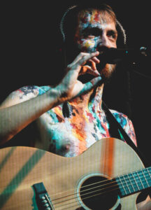 Man with a guitar singing into a microphone