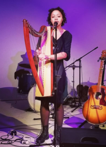 Woman playing a harp and singing into a microphone